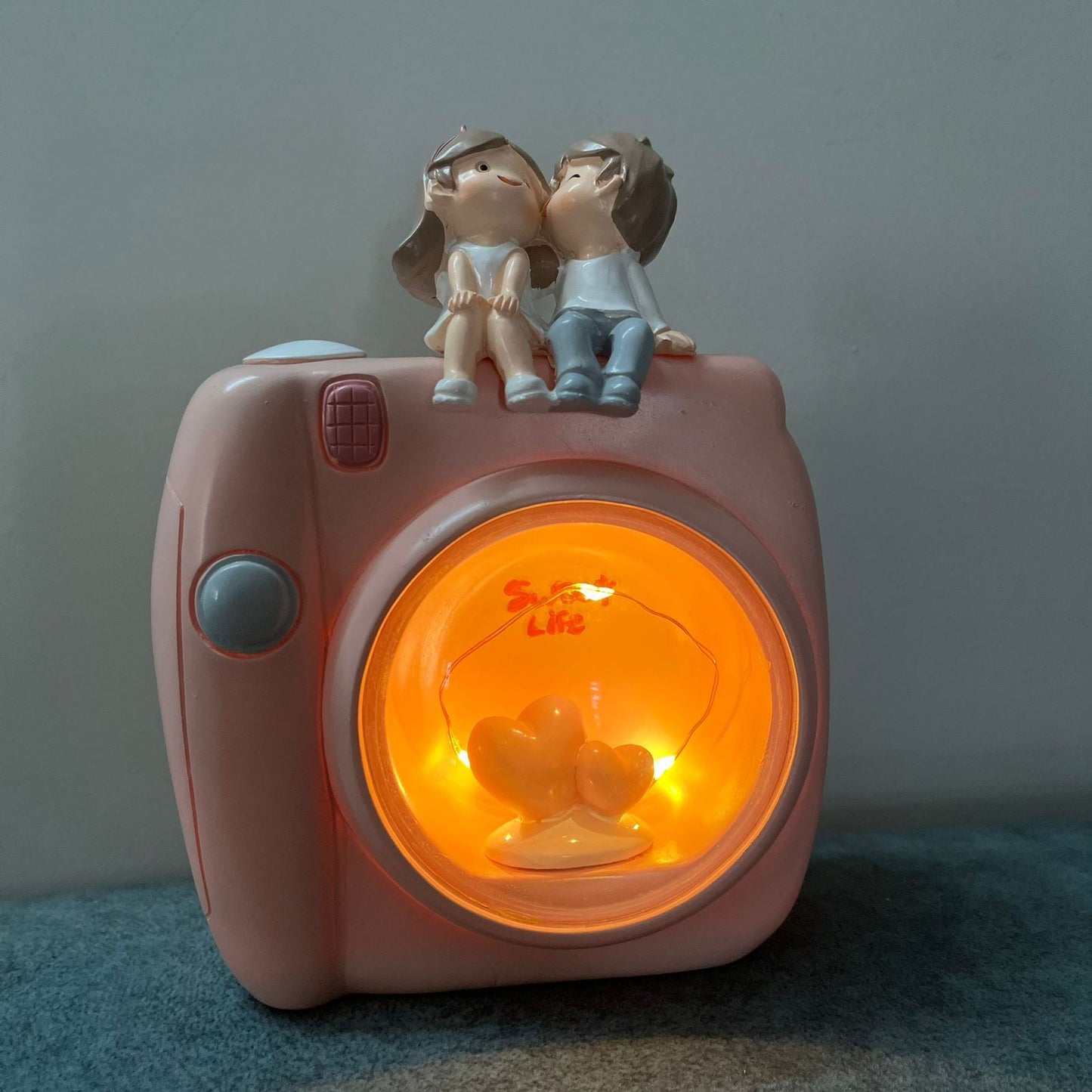 Couple Sitting On Camera Lamp -